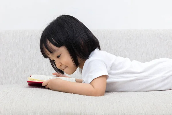 Glücklich asiatische chinesische kleine Mädchen legen auf Sofa mit Buch — Stockfoto