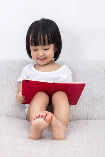 Feliz asiática china niña sentada en sofá con libro — Foto de Stock