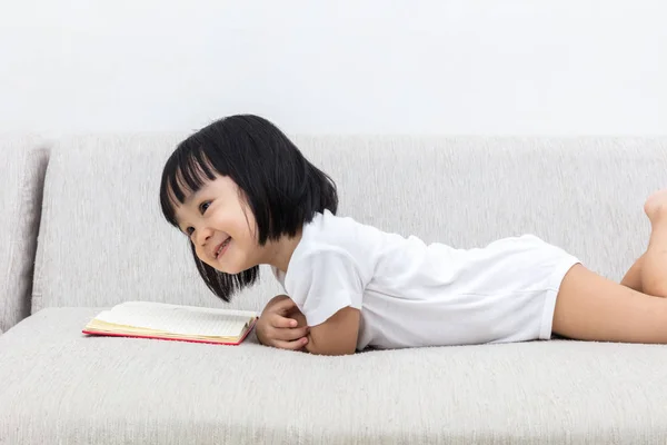 Felice asiatico cinese bambina posa su divano con libro — Foto Stock