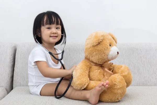 Asyalı Çinli küçük kız bir oyuncak ayı kontrol — Stok fotoğraf
