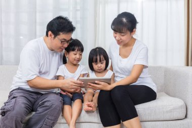 Asya Çin anne ve kızı koltukta tablet kullanma