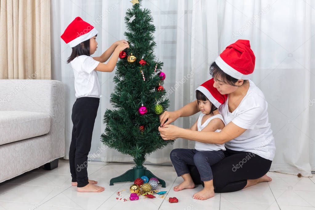 Asian Chinese mother and daughters decorating Christmas tree at 