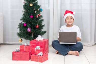 Asyalı Çinli küçük çocuk Noel yanında dizüstü bilgisayar ile sunar