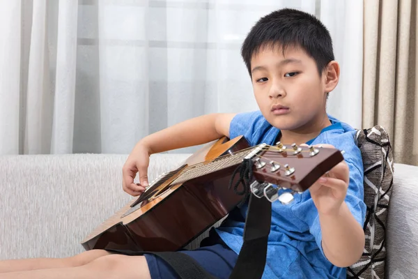 Asyalı Çinli küçük çocuk kanepede gitar çalmak — Stok fotoğraf