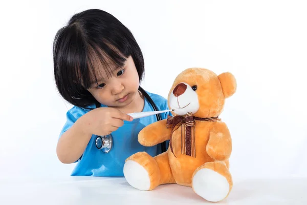 Asiatiska kinesiska liten flicka undersöka nallebjörn med termometer — Stockfoto