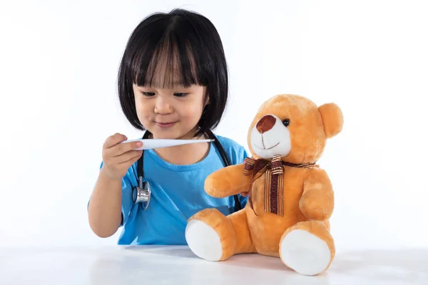 Felice asiatico cinese bambina esaminare orsacchiotto con thermome — Foto Stock