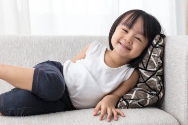 Mutlu Asyalı Çinli küçük kız kanepede uzanmış