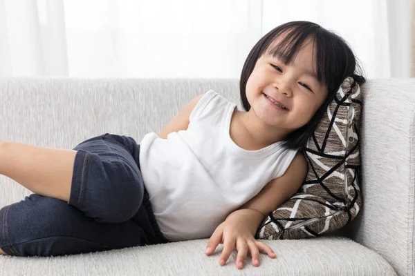 Glad asiatiska kinesiska liten flicka liggande på soffan — Stockfoto