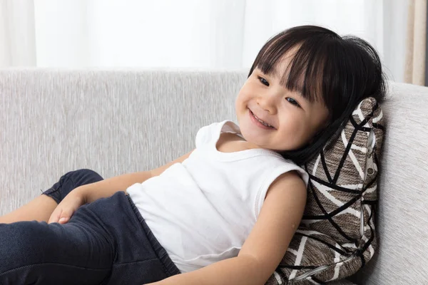 Szczęśliwy azjatycki chiński dziewczynka leżenia na kanapie — Zdjęcie stockowe