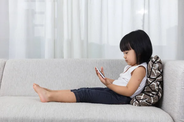 Asiática china niña acostada en el sofá con el teléfono — Foto de Stock