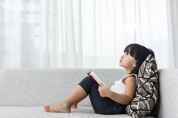 Asiatisch chinesisch klein mädchen thinking während reading auf die sofa — Stockfoto