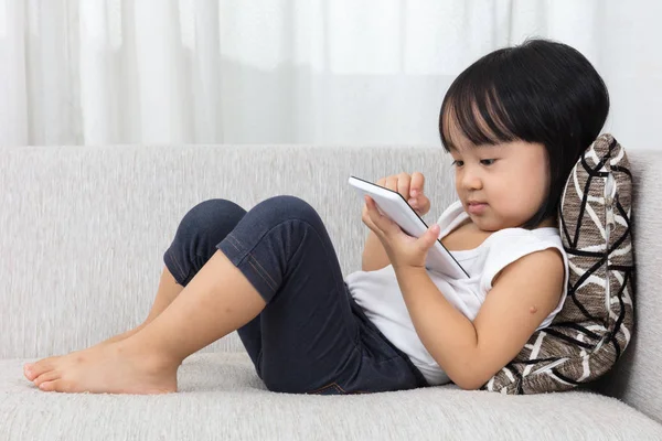 Asiática china niña acostada en el sofá con el teléfono — Foto de Stock