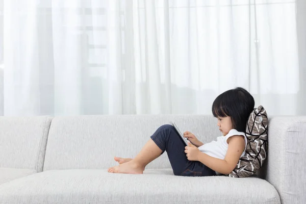 Asiática china niña acostada en el sofá con la tableta — Foto de Stock