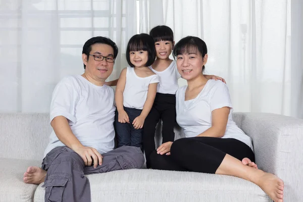 Happy Asian Chinese family sitting on the couch at home