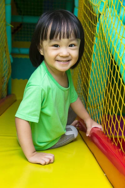Happy Asian Chinese little girl playing slide at indoor playgrou — Stock Photo, Image