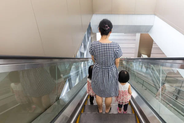 Asian Chinese mother and daughters taking escalator at MRT Stati