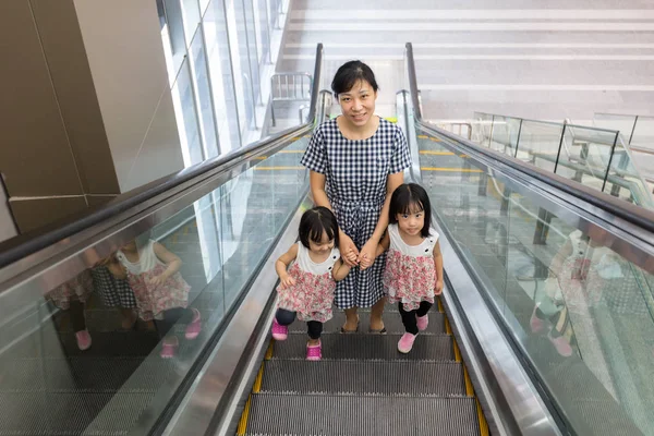 Asian Chinese mother and daughters taking escalator at MRT Stati
