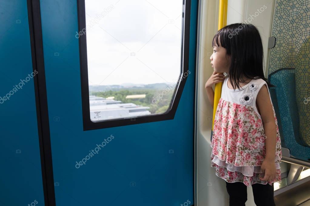 Asian Chinese little girl inside train looking beside the window