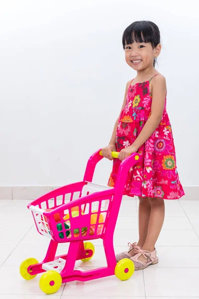 Happy Asian Chinese little girl pushing toy trolley — Stock Photo, Image