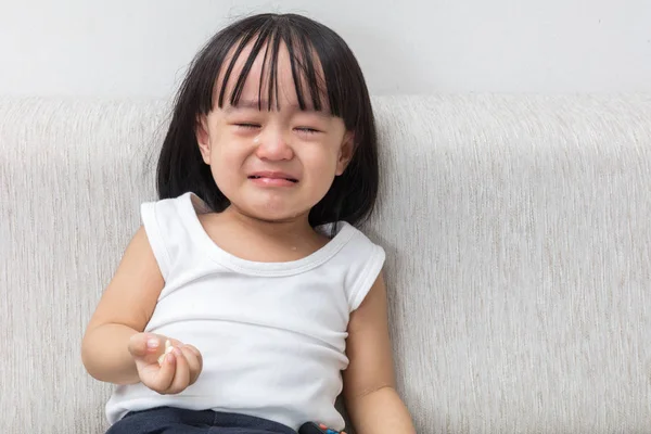 Asian Chinese little girl sitting on the sofa crying — Stock Photo, Image
