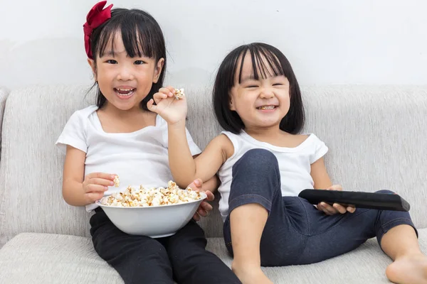 Felice asiatico cinese sorelline mangiare popcorn sul divano — Foto Stock