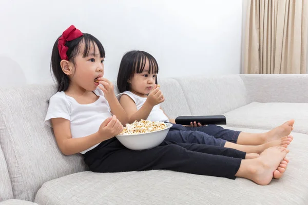 Asiatico cinese sorelline mangiare popcorn su il divano — Foto Stock