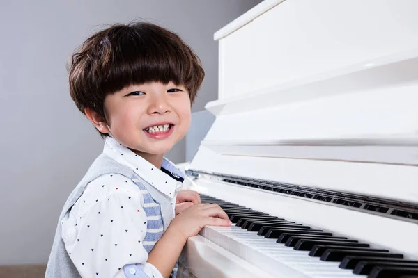 Счастливый азиатский китайский мальчик играет на пианино дома — стоковое фото
