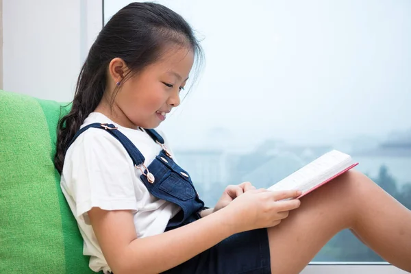 Asiatisch chinesisch klein mädchen lektüre buch auf der fensterbank — Stockfoto