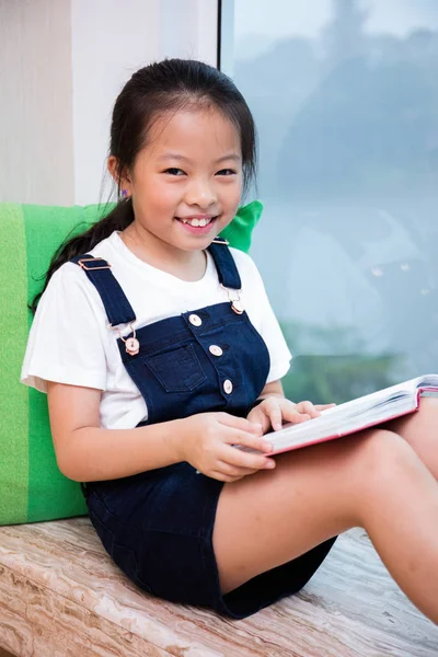 Aziatische Chinese meisje lezen boek op de vensterbank — Stockfoto