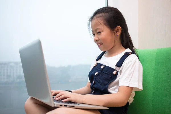 Asiatisch chinesisch klein mädchen using laptop auf die fensterbank — Stockfoto