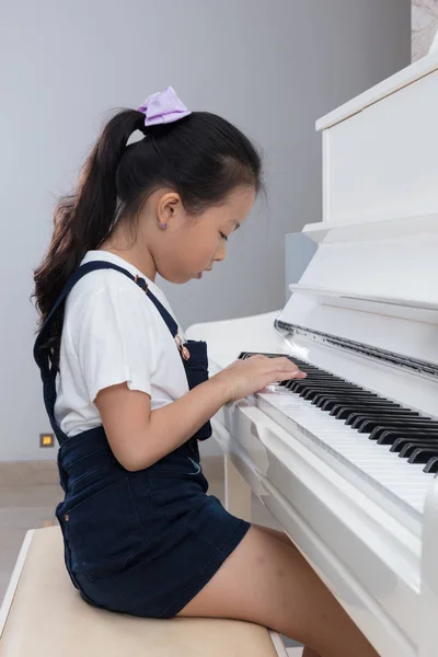 Asian Chinese little girl playing classical piano at home