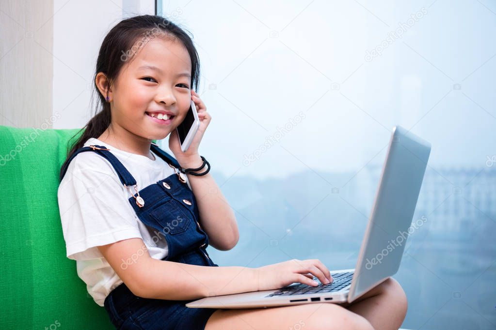 Asian Chinese little girl talking over phone with laptop