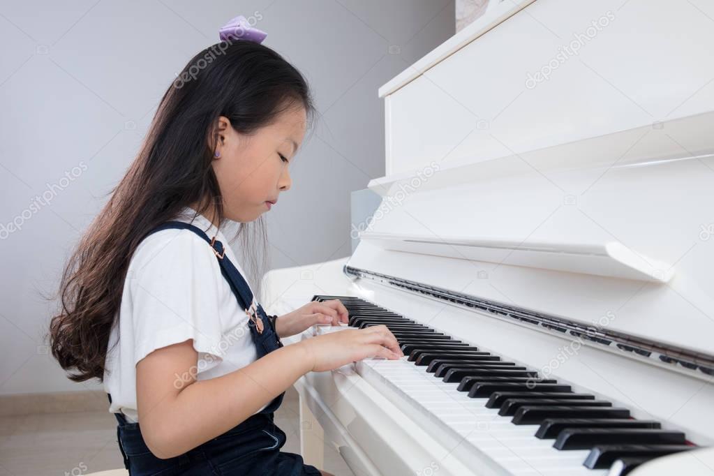 Asian Chinese little girl playing classical piano at home