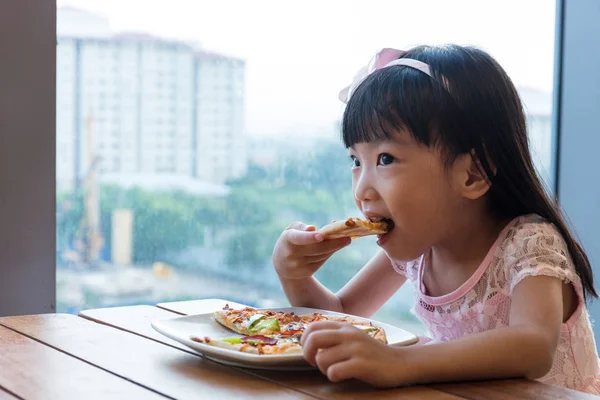 Asiatiska kinesiska lilla flicka äter pizza pepperoni — Stockfoto