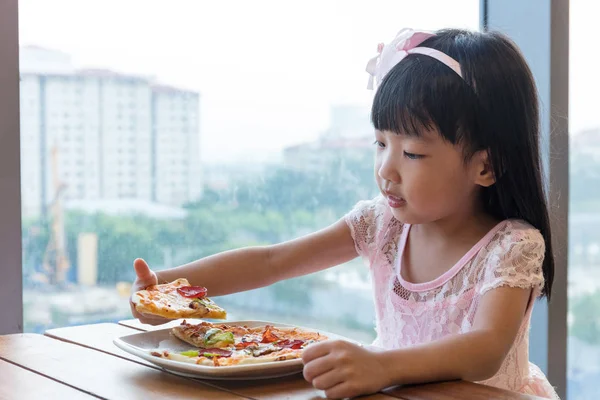 Asiatiska kinesiska lilla flicka äter pizza pepperoni — Stockfoto