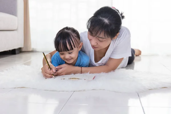 Gelukkig Aziatische Chinese moeder en dochter schrijven op de verdieping — Stockfoto