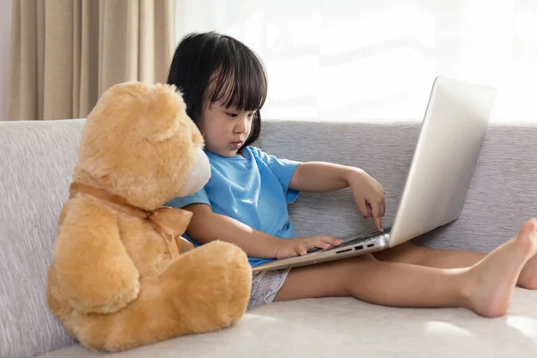 Asiática china niña usando portátil con osito de peluche — Foto de Stock