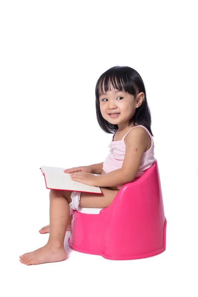 Asiatico cinese bambina seduta su chamberpot con libro — Foto Stock
