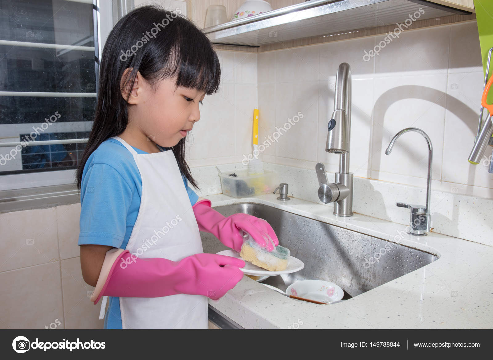Asian Chinese Little Girl Washing Dishes In The Kitchen