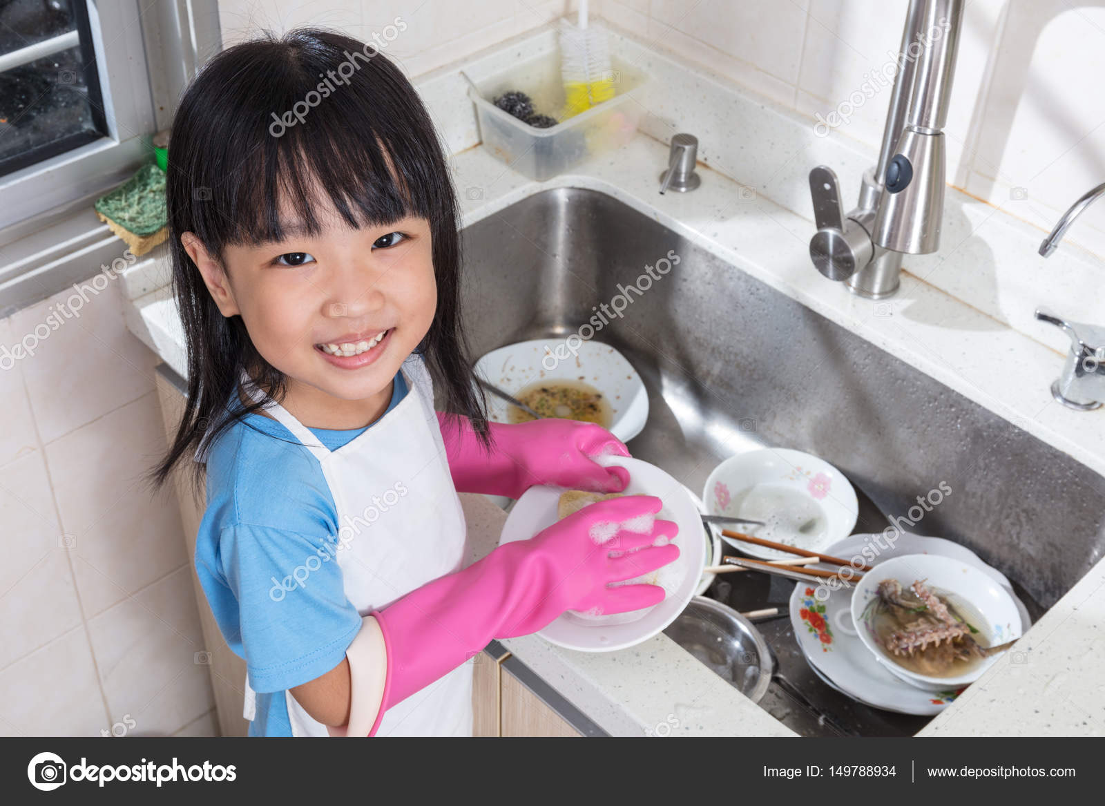 Asian Chinese Little Girl Washing Dishes In The Kitchen