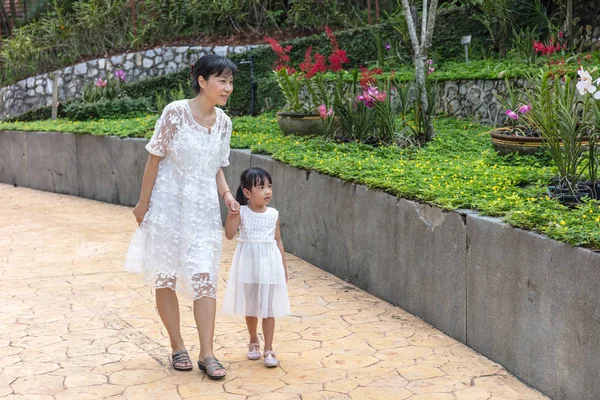 Mãe asiática andando com a filha no jardim ao ar livre — Fotografia de Stock