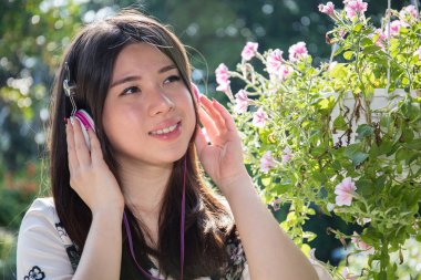 Asyalı güzel genç kadın bahçede Kulaklık takmış