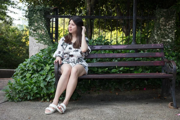 Asiático hermosa joven mujer sentado en banco en al aire libre jardín —  Fotos de Stock