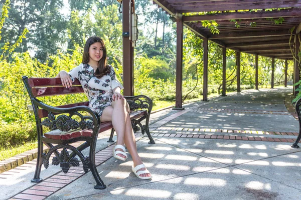 Asiático hermosa joven mujer sentado en banco en al aire libre jardín —  Fotos de Stock