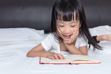Asyalı küçük Çinli kız yatakta kitap okuma