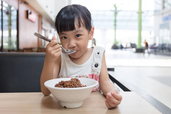 Asiática menina chinesa comendo arroz de porco refogado — Fotografia de Stock