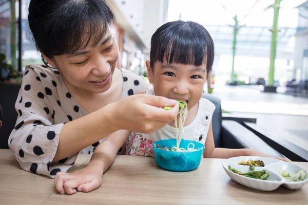 Asian Chinese mother and daughter eating beef noodles — Stock Photo, Image