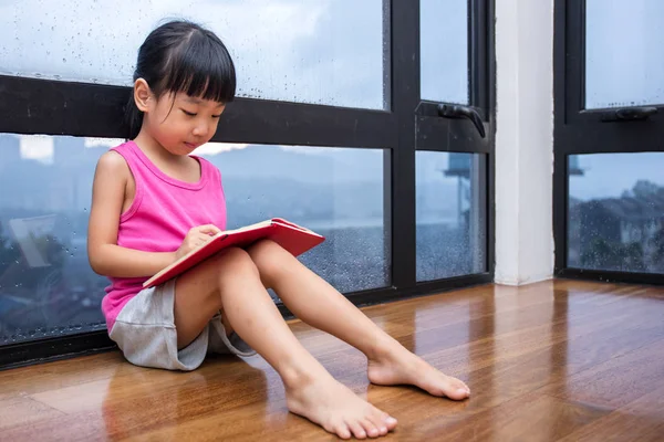 Asiatische kleine chinesische Mädchen lesen ein Buch in der Nähe des Fensters — Stockfoto