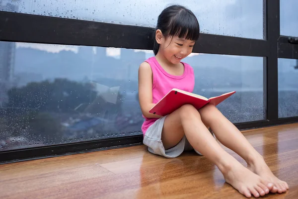 Asiatische kleine chinesische Mädchen lesen ein Buch in der Nähe des Fensters — Stockfoto