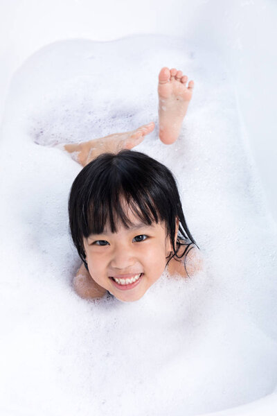 Asian little Chinese girl playing with water and foam